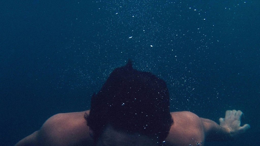 person underwater surrounded by small bubbles
