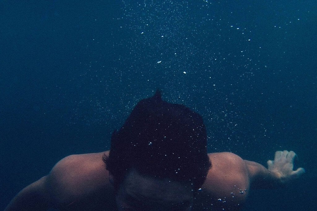person underwater surrounded by small bubbles