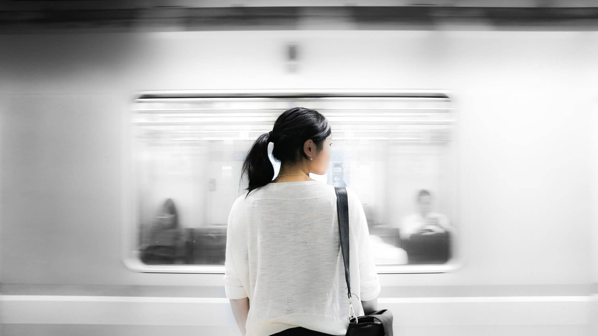 woman standing on train platform as train rushes by