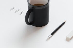 paperclips, coffee mug, pencil, and eraser set up in a line