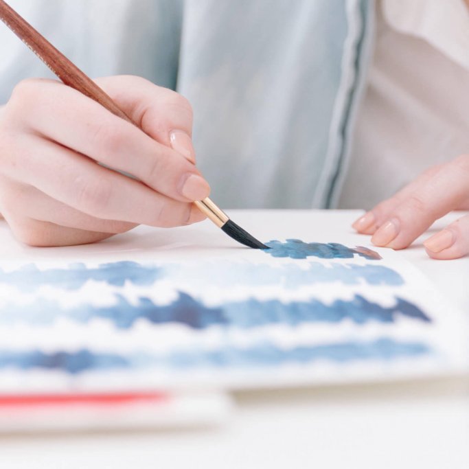 person painting blue lines on paper