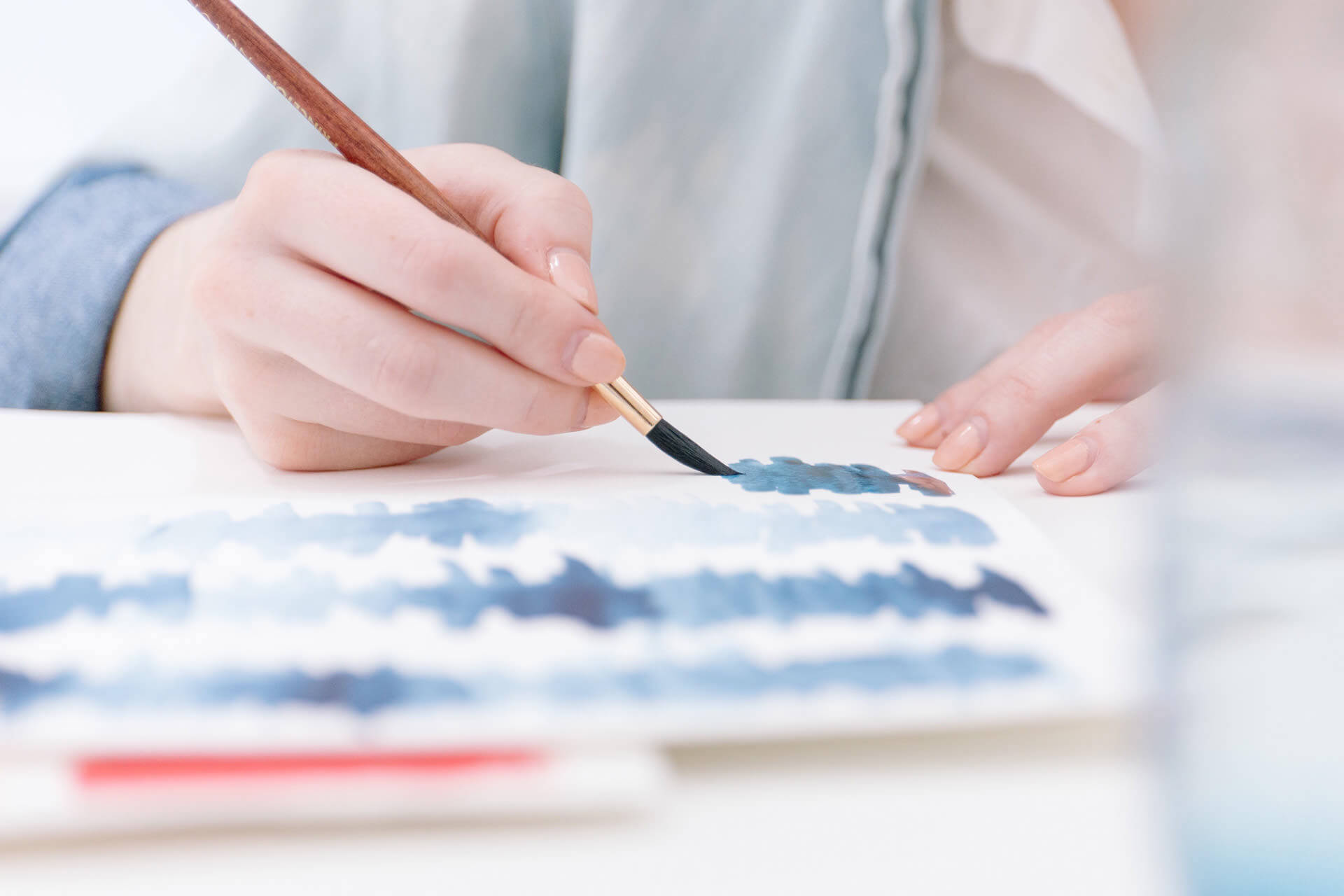 person painting blue lines on paper