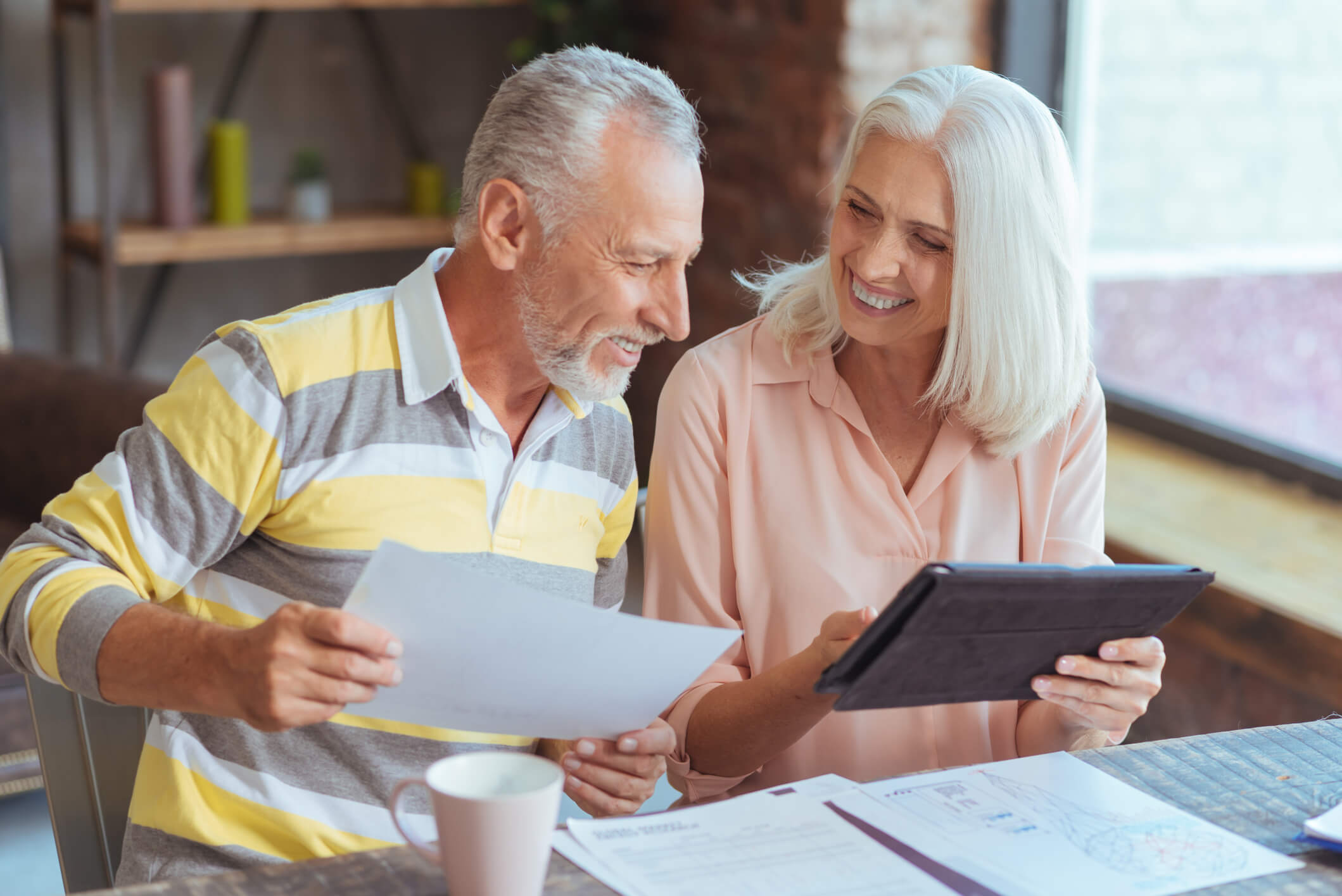 Cheerful loving aged couple involved in paperwork at home